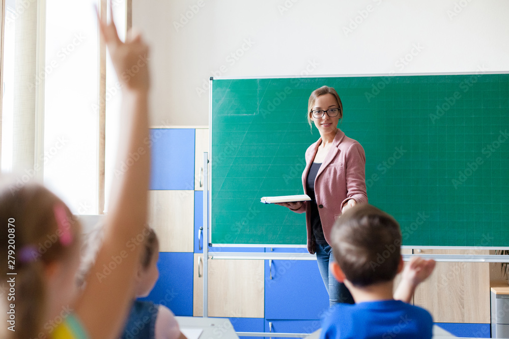 Female primary school teacher standing in a classroom gesturing to