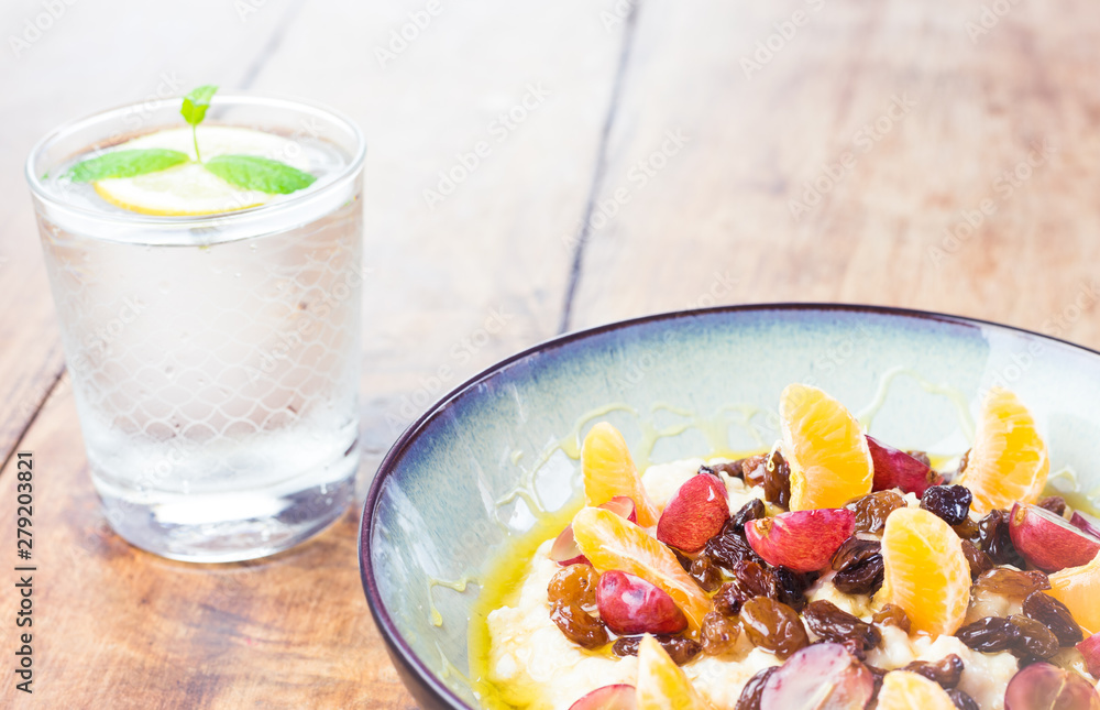 Healthy breakfast - oatmeal with tasty fruit and glass of water with lemon Healthy breakfast - oatmeal with tasty fruit and glass of water with lemon