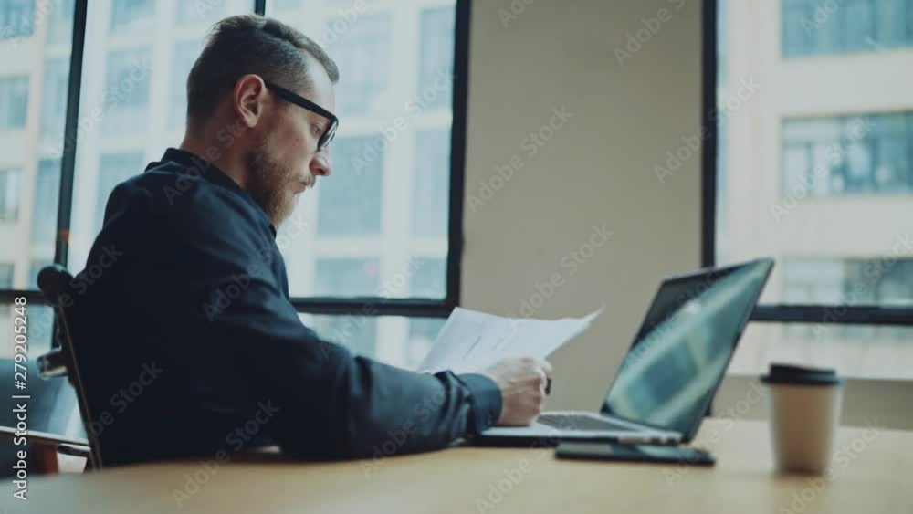 Bearded businessman man working at sunny office on desktop computer while sitting at wooden table. Bearded businessman man working at sunny office on desktop computer while sitting at wooden table.