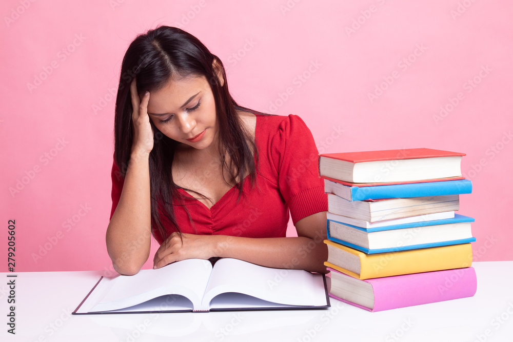 Exhausted Young Asian woman read a book with books on table. Exhausted Young Asian woman read a book with books on table.