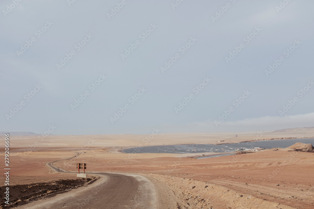 A dirt track and ocean in the background against blue sky,Paracas,Peru