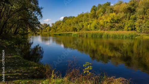 Autumn deciduous forest  water river and the river bank on a sunny day. Amazing landscape.