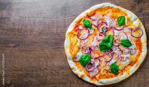 Pizza with Mozzarella cheese, ham, tomato sauce, onion, pepper, Spices and Fresh basil. Italian pizza on wooden table background