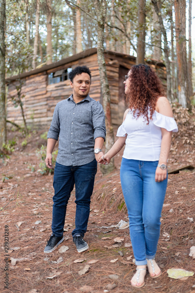 Couple walking holding hands smiling in the forest- full body Couple walking holding hands smiling in the forest- full body