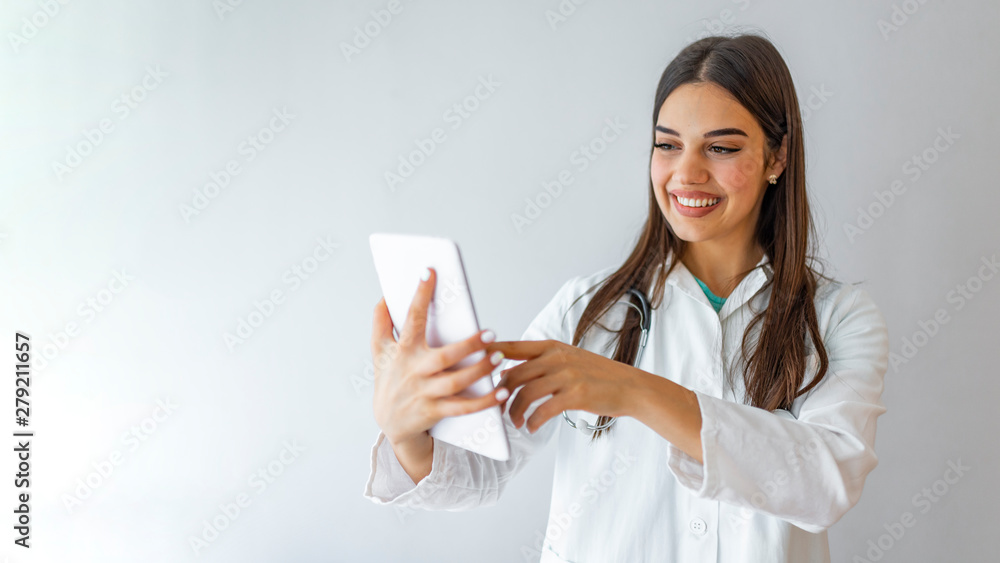 Fototapeta premium Healthcare, technology and medicine concept - smiling female doctor with stethoscope and tablet pc computer. Young happy medical worker using tablet computer.