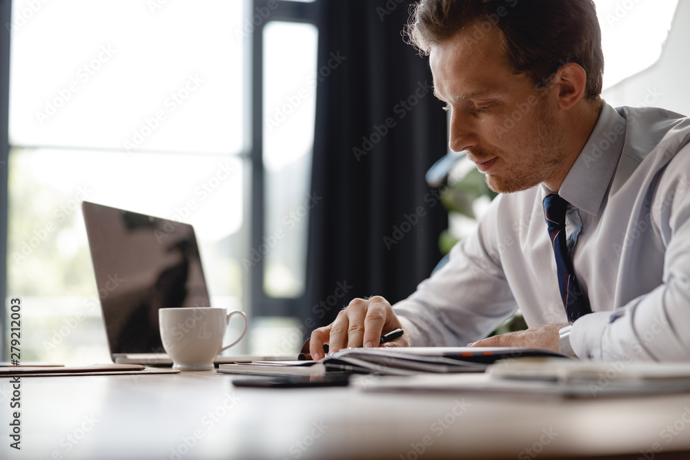 Calm man looking at the notes while working in office