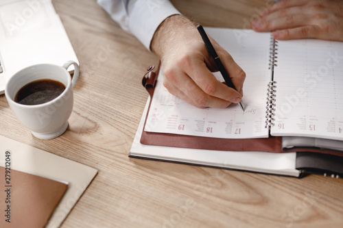 Man writing in daily planner with black pen