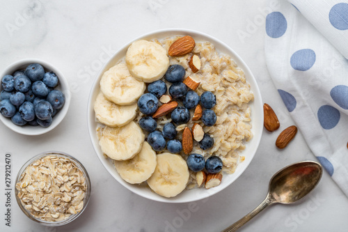 Oatmeal porridge with blueberries, almonds and banana on marble table photo