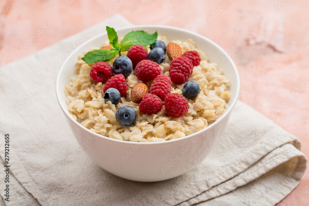 Oatmeal with raspberries, almonds and blueberries and mint  on pink background