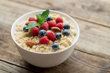 Oatmeal with raspberries, almonds and blueberries and mint on old wood background