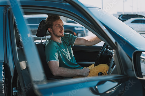 Handsome young man in shirt sitting in the car