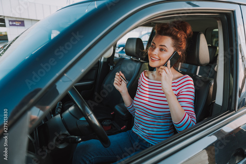 Cheerful young woman talking on cellphone in car