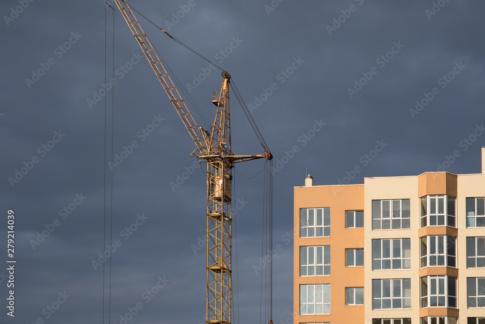 Industrial construction building crane against dark cloudy sky Industrial construction building crane against dark cloudy sky