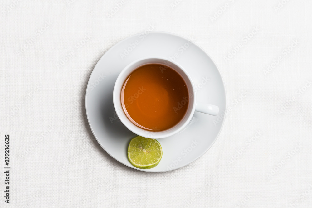 Hot lemon drink with lemon on textured cloth background. Top view. 