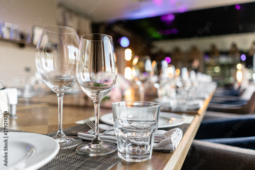 Wine glasses in the foreground. Wedding Banquet or gala dinner. The chairs and table for guests, served with cutlery and crockery. Wine glasses in the foreground. Wedding Banquet or gala dinner. The chairs and table for guests, served with cutlery and crockery.