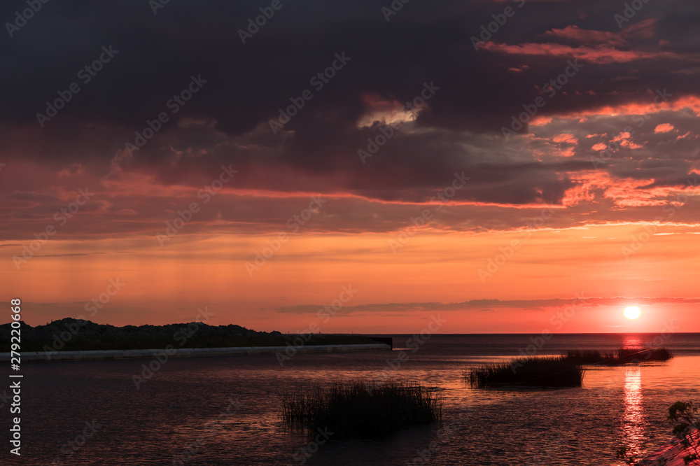 Bright, colorful, red sunset. The river flows into the Gulf of Finland. Summer. Late evening.