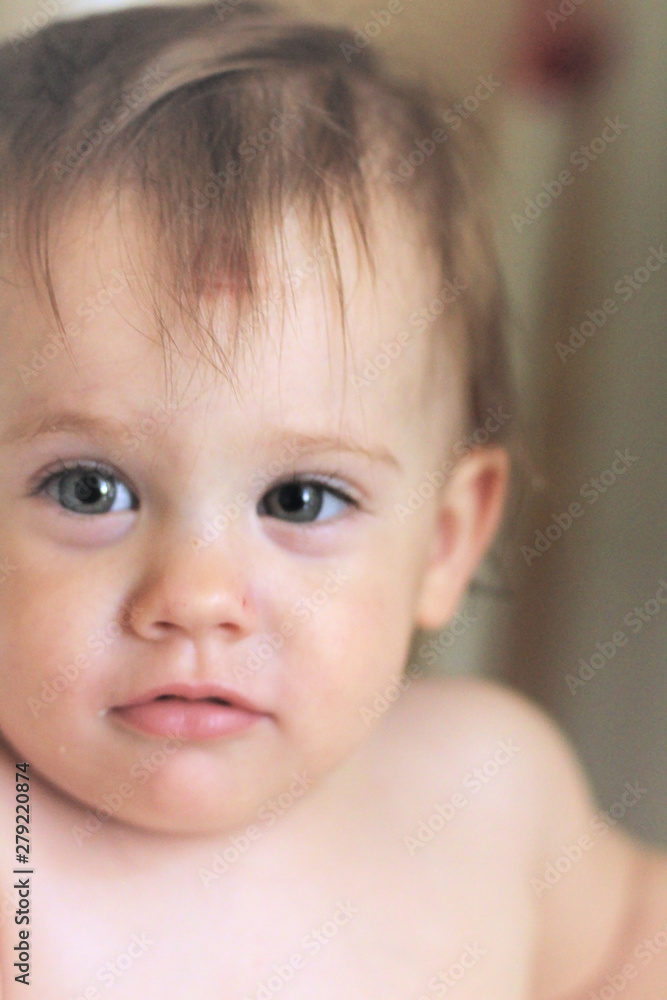 Close-up portrait of a cute smiling little white baby sitting in a chair without clothes Close-up portrait of a cute smiling little white baby sitting in a chair without clothes