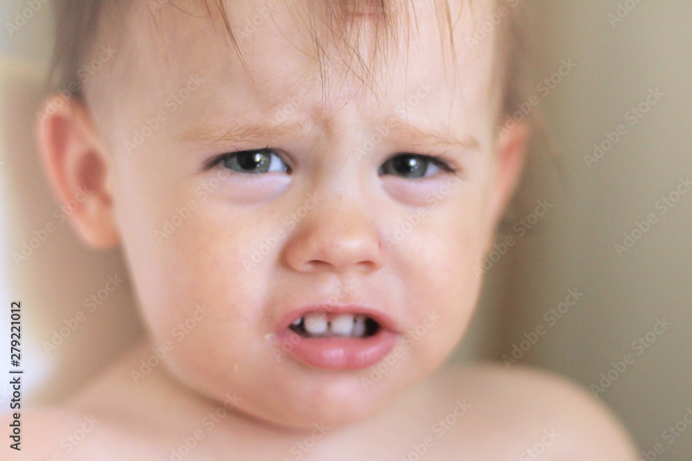 Close-up portrait of a cute smiling little white baby sitting in a chair without clothes Close-up portrait of a cute smiling little white baby sitting in a chair without clothes