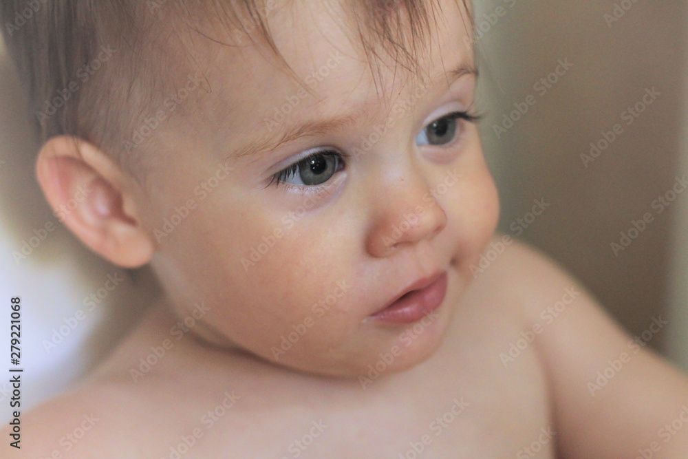 Close-up portrait of a cute smiling little white baby sitting in a chair without clothes Close-up portrait of a cute smiling little white baby sitting in a chair without clothes
