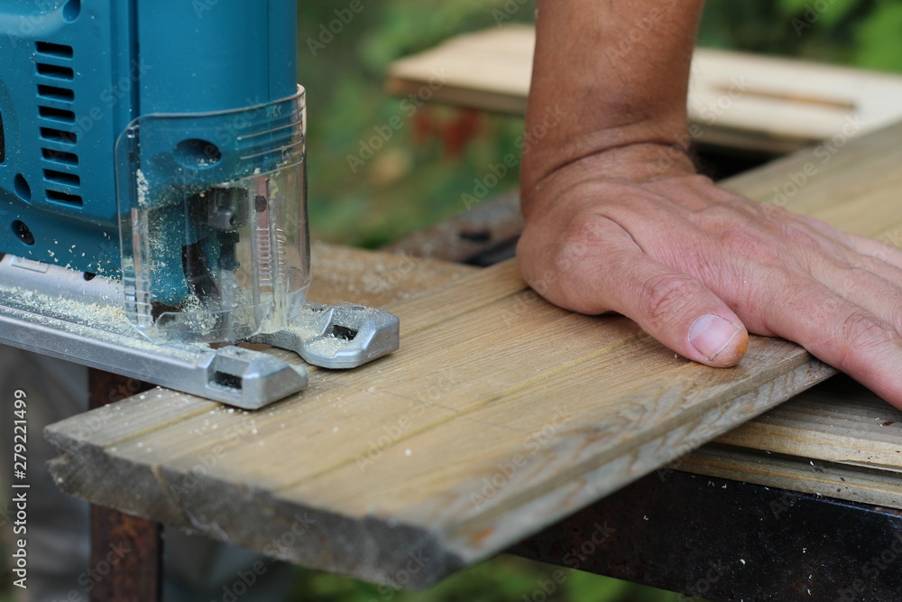 Carpenter with fretsaw at outdoor work. close-up