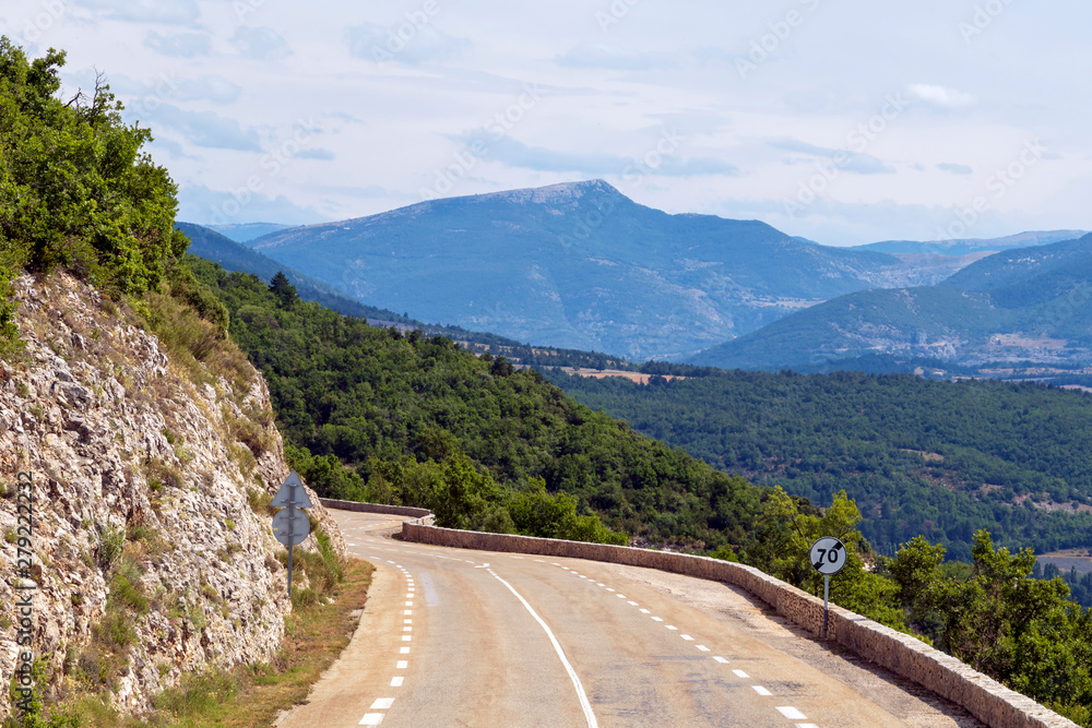 Mountain road curve above the forest and agricultural fields in French countryside