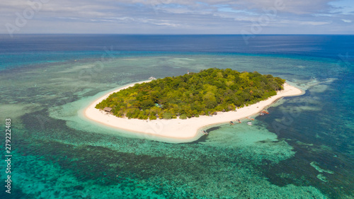A small island surrounded by azure water and coral reefs, a top view.Round tropical island with white sandy beach, top view.Mantigue Island, Philippines.