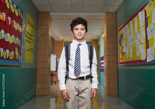 Portrait of school boy (10-11) standing with backpack in school corridor
