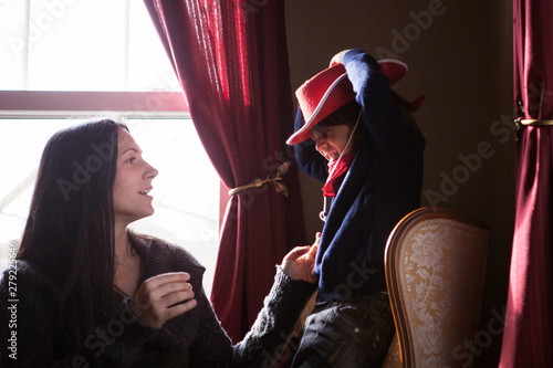 Little boy (4-5) playing with mother by window