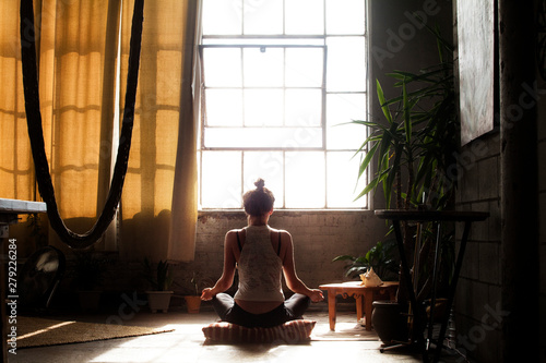 Slika na platnu Rear view of woman meditating in living room