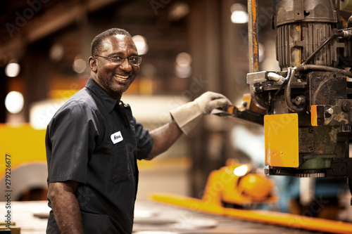 Canvas-taulu Smiling mature worker using machinery in factory