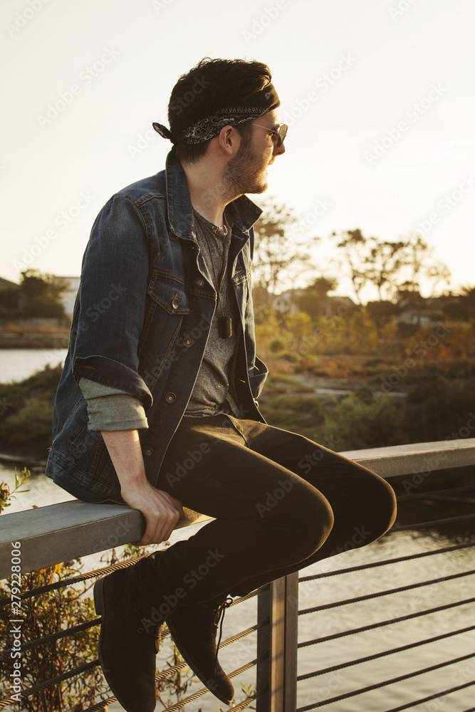 Fototapeta premium Young man sitting on railing,