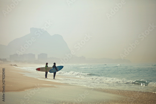 Photography Couple with surfboards standing on beach