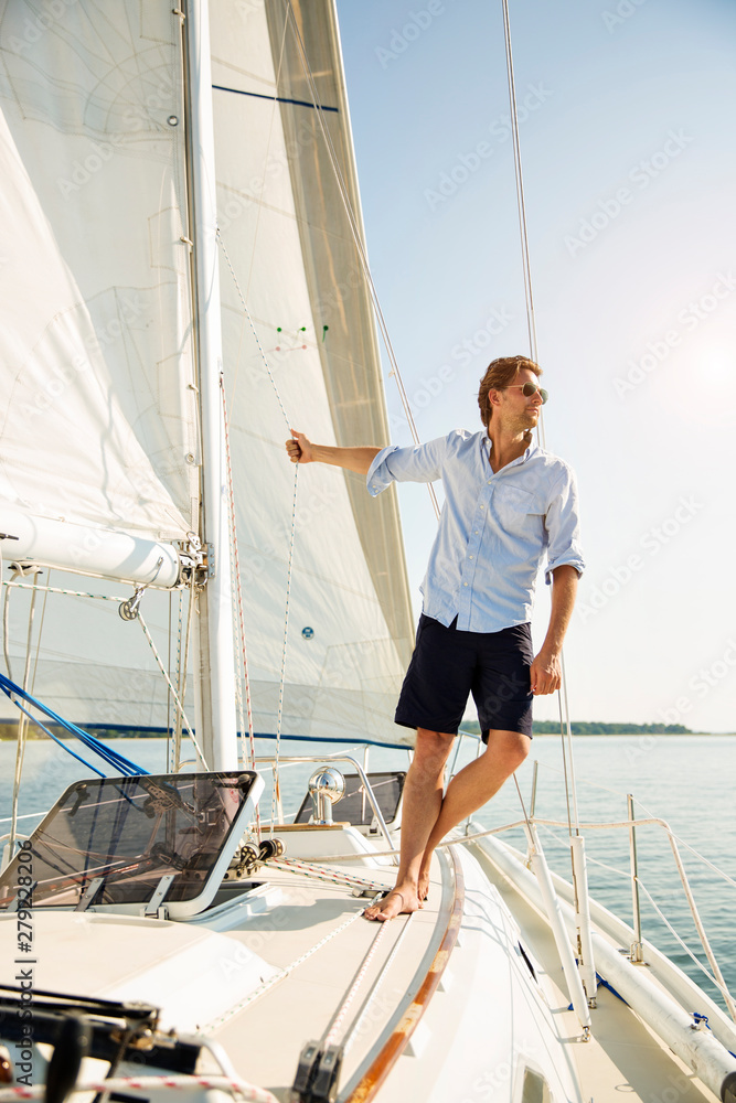 Fototapeta premium Man leaning off sails of private yacht