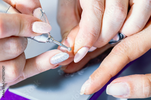 A session of a hardware manicure in the salon  treatment with a round cutter.