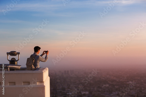 Man taking picture of city with smartphone from observation point