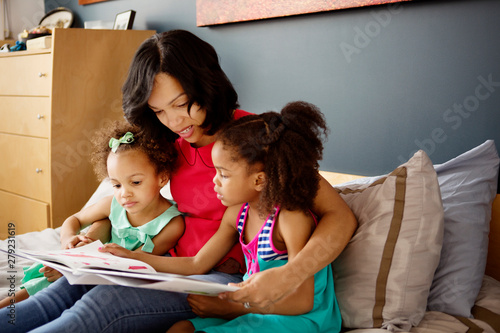 Canvas Print Mother reading to daughters (2-3, 4-5) in bedroom