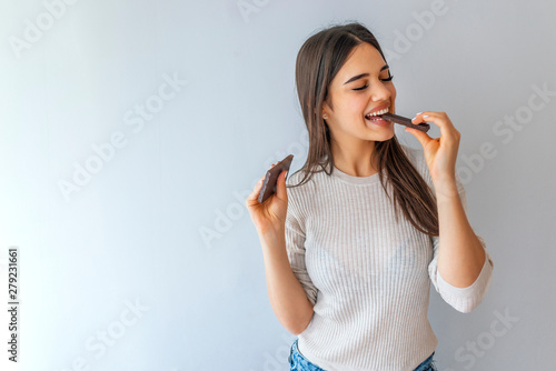 Tableau sur toile Portrait of a young beautiful girl with dark hair, holding a chocolate bar to enjoy the taste and are dieting, healthy eating and organic foods, feeling temptation
