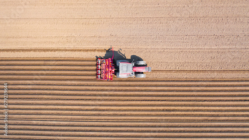 Tractor on a plowed field, top view. Agricultural field for planting vegetables. Tractor makes furrows on the field.