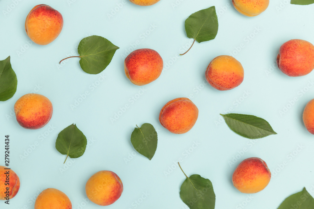 Obraz premium Apricots on a blue background, the flat lay image of ripe apricots and leaves