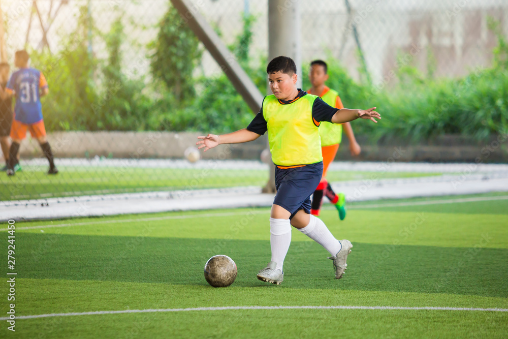 Soccer player speed run on green artificial turf to shoot ball to goal. Boy soccer player is training. Asian boy player is in football academy.