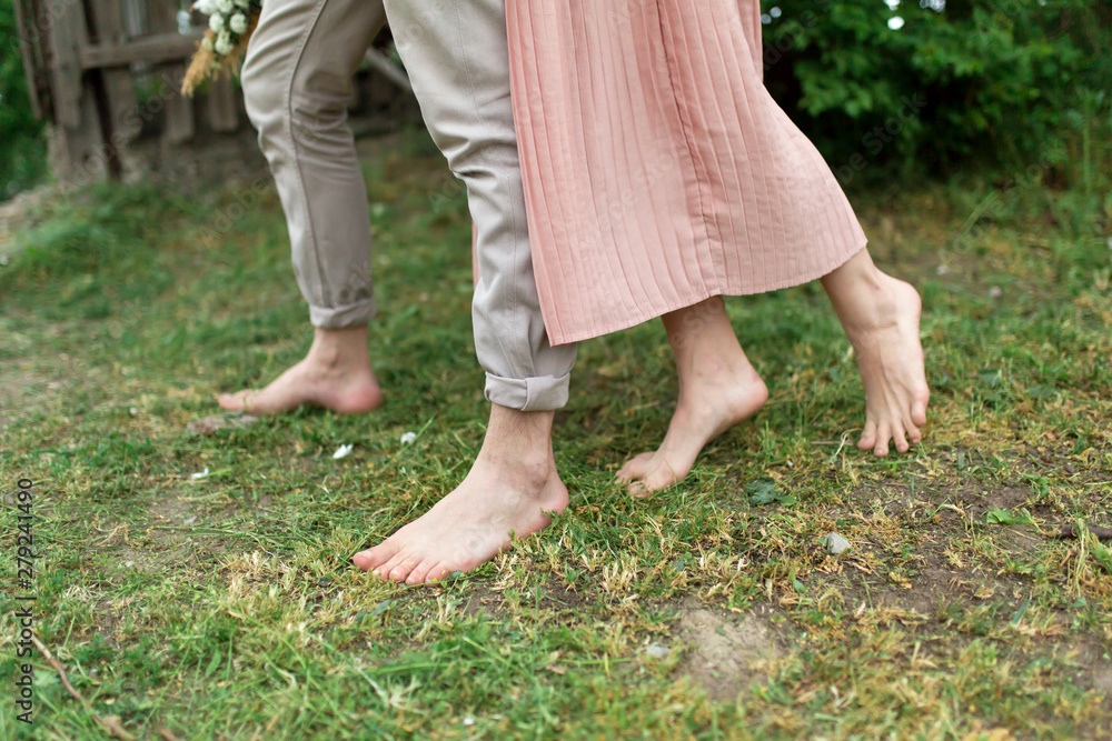 Young loving couple hugging and dancing on the green grass on the lawn. Beautiful and happy woman and man gently touch each other. Beautiful couple in love. girl in the dress and the guy in the shirt Young loving couple hugging and dancing on the green grass on the lawn. Beautiful and happy woman and man gently touch each other. Beautiful couple in love. girl in the dress and the guy in the shirt