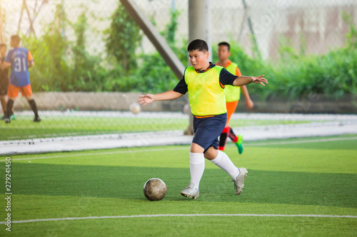 Soccer player speed run on green artificial turf to shoot ball to goal. Boy soccer player is training. Asian boy player is in football academy. © Koonsiri