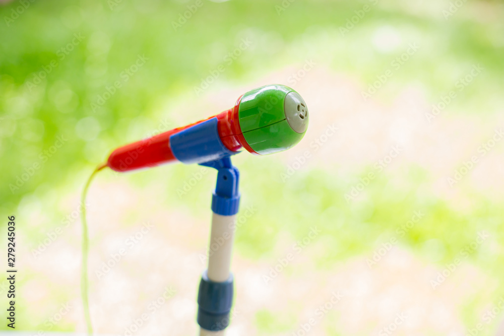 selective focus to colorfull toy microphone on blurry green background. the concept of kid speaker or learning speech.