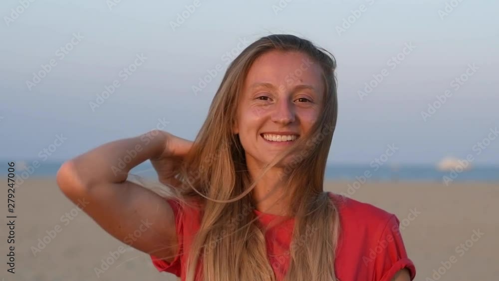 Portrait of happy woman smiling on the beach at sunset in slow motion Portrait of happy woman smiling on the beach at sunset in slow motion