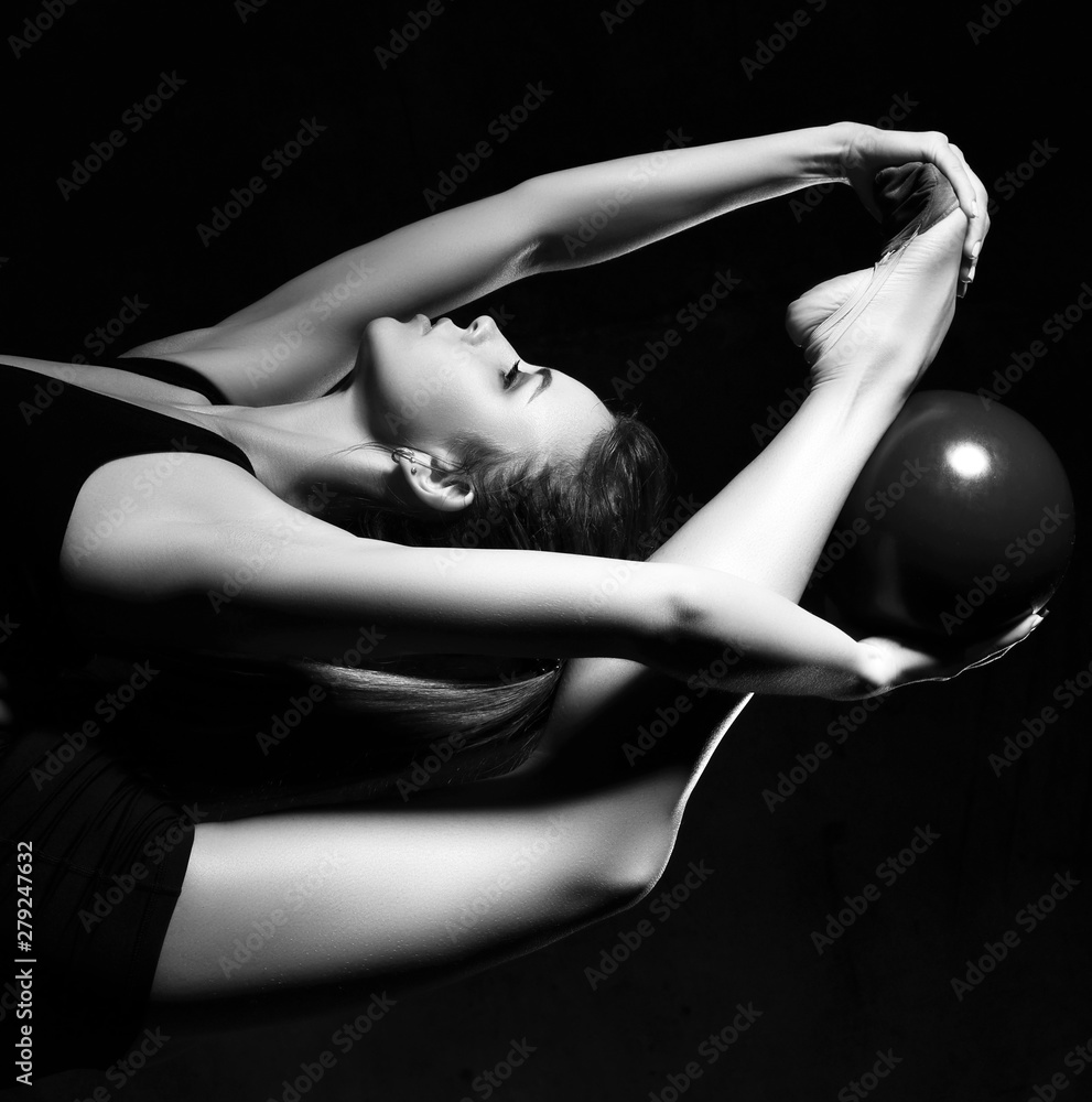Naklejka premium Young sporty woman doing gymnastics stretching fitness exercises workout with ball in sport club