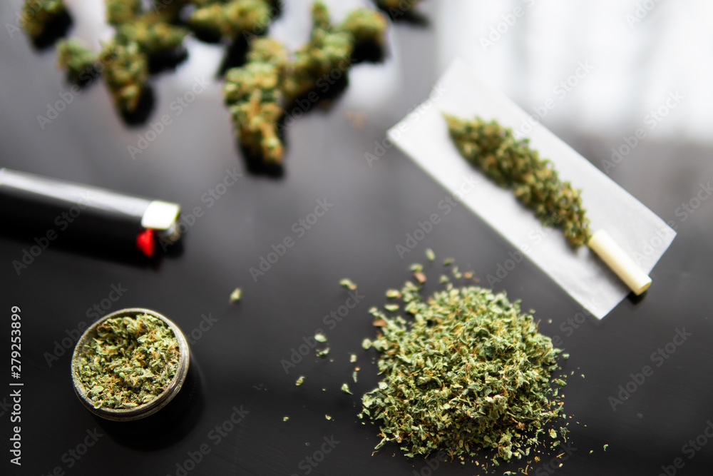 Herb grinder Fresh marihuana. Blunt and Lighters. Close up. Cannabis buds  in hand on black background Background for Copy space. CBD and THC on buds  in cannabis. Stock Photo