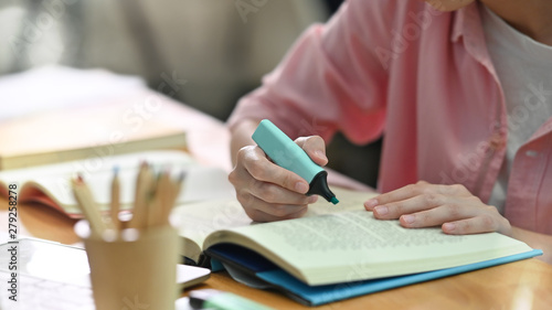 Cropped shot young female using highlight pen on book with education lesson concept.