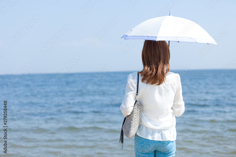 海辺で日傘を差す女性の後姿