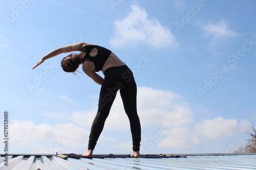 Young attractive woman doing yoga outdoors . Warming up and stretching.