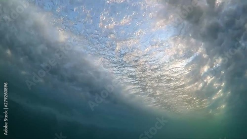 Slow motion underwater footage of boat hull passing very close with sunlight shining through water. photo